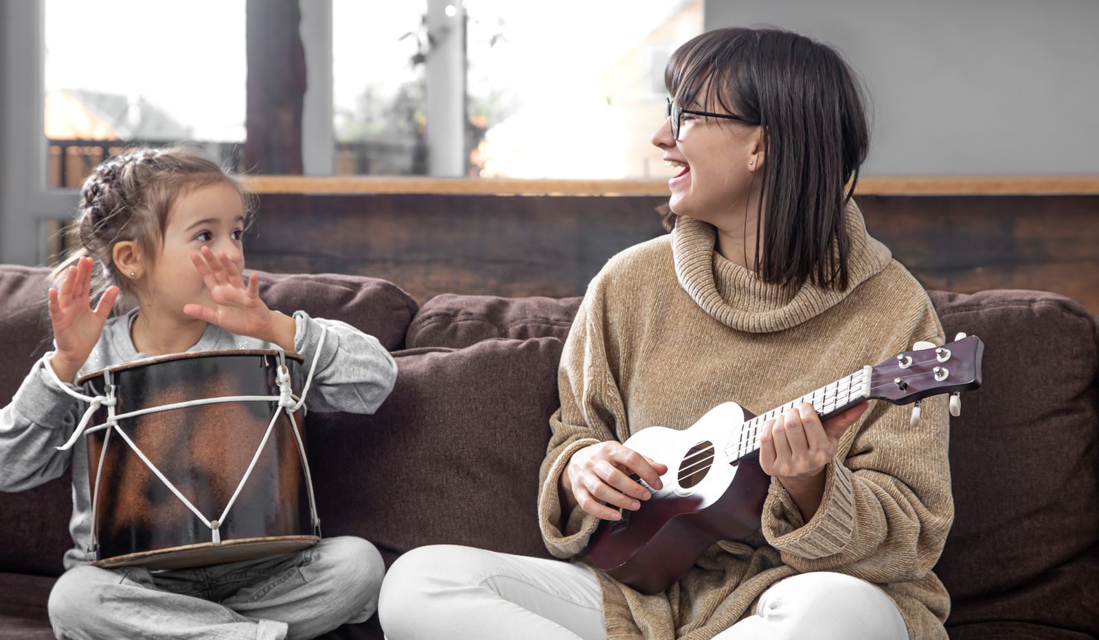 Maman et enfant jouant de la musique ensemble sur un canapé